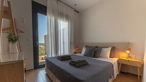 Un dormitorio moderno con una cama grande, un aparador de madera y un escritorio con lámpara.