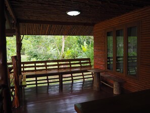 A wooden bench and table on a porch with a view of lush greenery. - Pru Valley Thaley Tai Resort (Chumphon)
