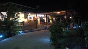 A building with a covered outdoor area, a concrete pathway, and surrounding greenery. - Pru Valley Thaley Tai Resort (Chumphon)