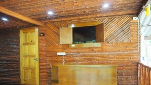 A log cabin interior with a wooden door, a built-in shelf, and a window with a view. - Pru Valley Thaley Tai Resort (Chumphon)
