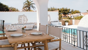 An outdoor patio with a wooden table set for dining, surrounded by white walls and a decorative archway. - Villa Boho Ibiza Style (Jávea)