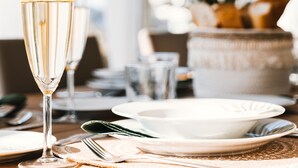 A table set for a meal with a glass of champagne, plates, cutlery, and a vase with flowers. - Villa Boho Ibiza Style (Jávea)