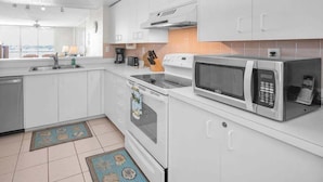 Una cucina moderna con mobili bianchi, un forno a microonde, una macchina da caffè e un lavastoviglie.