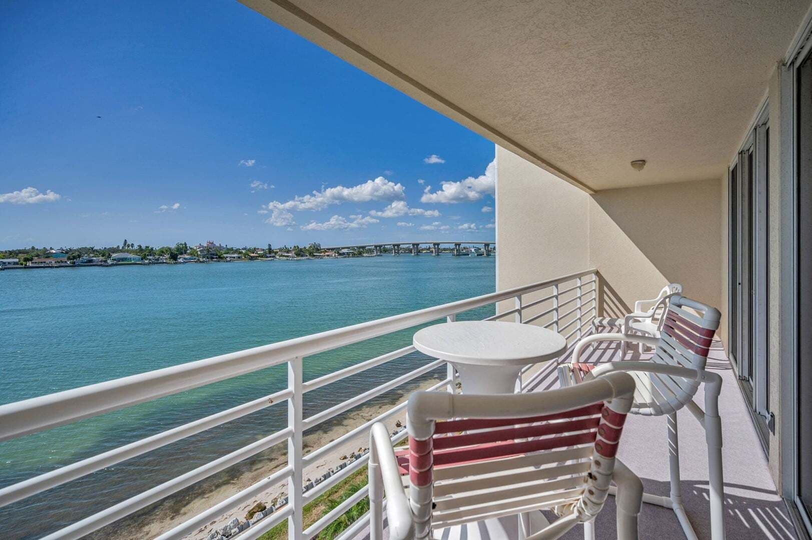 Un balcon offrant une vue sur une étendue d’eau, un pont et une côte lointaine.