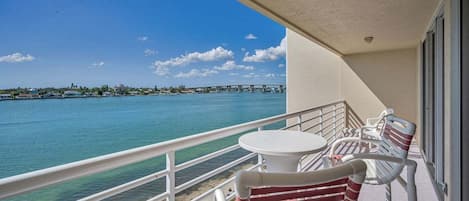A balcony with a view of a body of water, a bridge, and a distant shoreline.