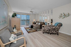 A spacious living room with a sofa, armchairs, a coffee table, and a view of the sea through large windows.