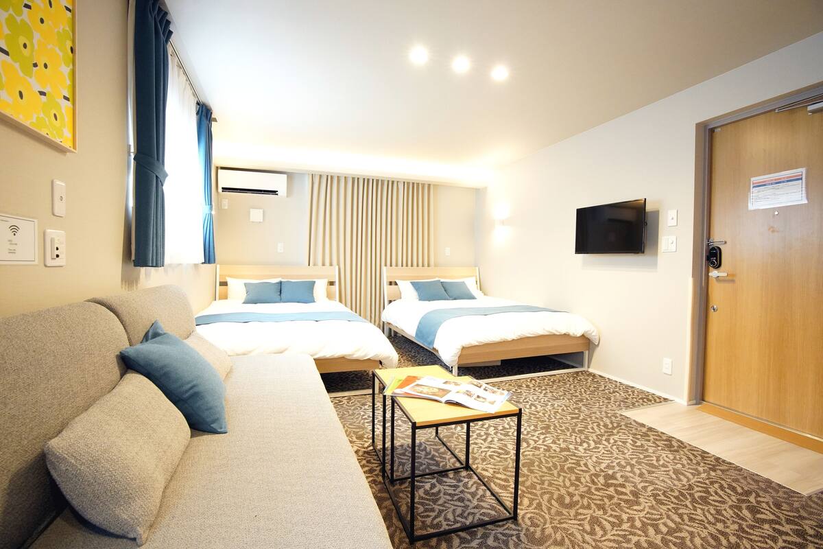 Habitación de hotel con dos camas, un sofá, una mesa de centro y un televisor.