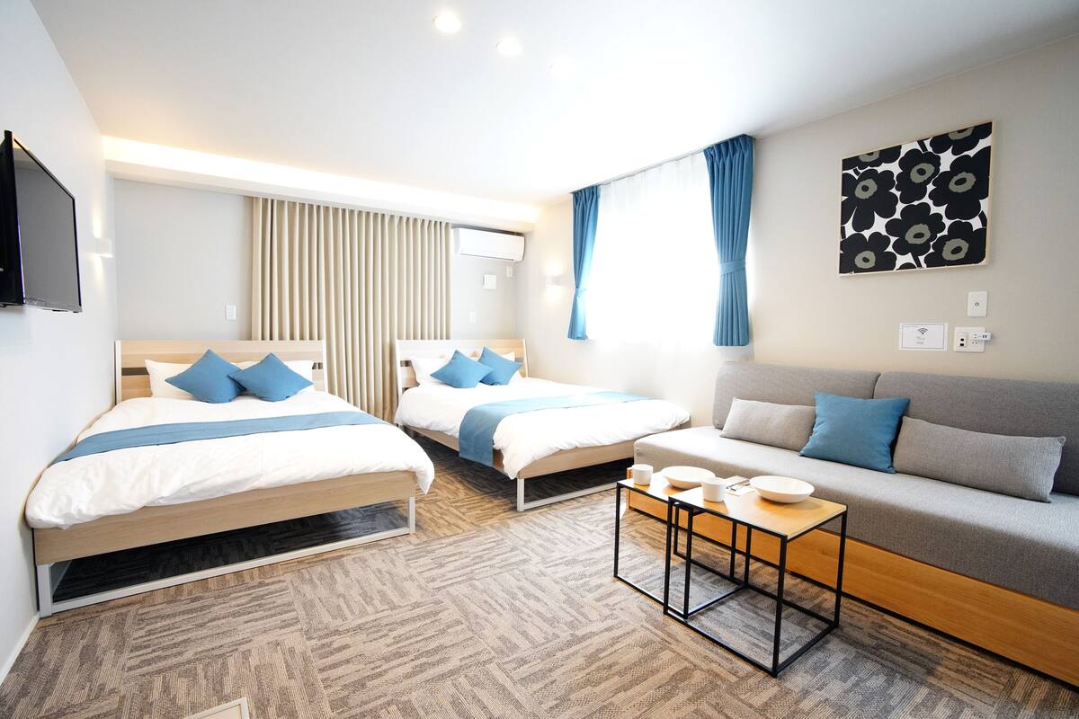 Una habitación de hotel moderna con dos camas, un sofá, una mesita de café y una televisión.