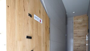 A hallway with a wooden door labeled "Luggage Room" and a grey tiled floor. - Koti Sopo Universal Bay 1 by Liaison (Osaka)