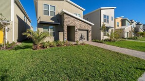A modern residential building with a stone facade, a garage, and a well-maintained lawn. - (WE2738) Storey Lake Home 5/5, Private Pool & Free Waterpark (Kissimmee)