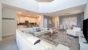 A spacious living area with a sectional sofa, a coffee table, and a dining area with chairs and a table. - (WE2738) Storey Lake Home 5/5, Private Pool & Free Waterpark (Kissimmee)