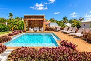A swimming pool with lounge chairs and a wooden deck.