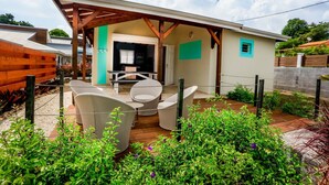 A covered patio area with a dining set and a wooden fence. - --- AIGUE-MARINE --- (Sainte-Anne)