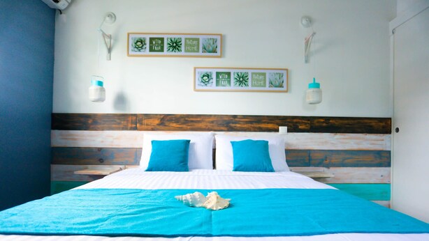 A bed with a blue and white bedspread, two blue pillows, and a white decorative item on the bed. - --- AIGUE-MARINE --- (Sainte-Anne)
