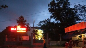 Een gebouw met een neonbord waarop staat 'Hill Crown'.