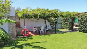 A backyard with a dining table and chairs, a lifebuoy, and a stone wall. - Chalet Dehesa Villa with private pool (CONIL DE LA FRONTERA)