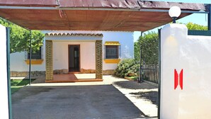 A house with a covered entrance, a stone pillar, and a gated driveway. - Chalet Dehesa Villa with private pool (CONIL DE LA FRONTERA)