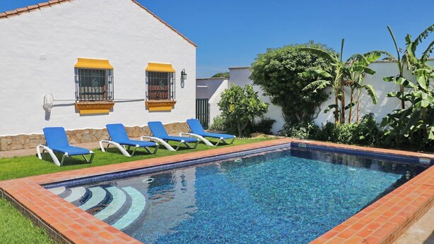 A rectangular swimming pool with blue tiles, surrounded by a brick border. There are blue lounge chairs aligned along the pool's edge. - Chalet Dehesa Villa with private pool (CONIL DE LA FRONTERA)