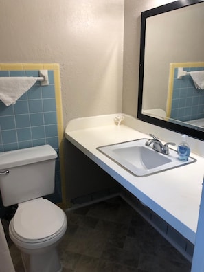 A compact bathroom with a toilet, sink, and mirror.