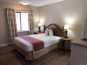 Relax in this inviting space with a comfortable bed, bedside lamps, and a window with curtains.