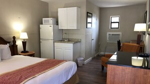 A hotel room with a bed, a desk, a refrigerator, a microwave, a sink, and a window. - Ocala Cove Motel (Ocala)