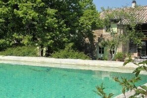 En klar swimmingpool med en stengbygning i baggrunden.