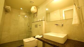 Casa de banho com cabine de duche em vidro, lavatório branco e espelho sobre o lavatório.