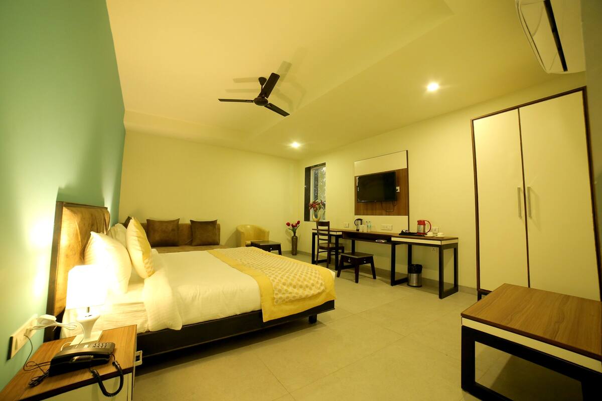 Een hotelkamer met een bed, bureau, stoel, kledingkast en plafondventilator.