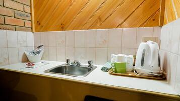 Una cocina con un fregadero, una tetera y una taza sobre la encimera.