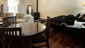 A living room with a round glass table, dark wooden chairs, a sofa, and a television.