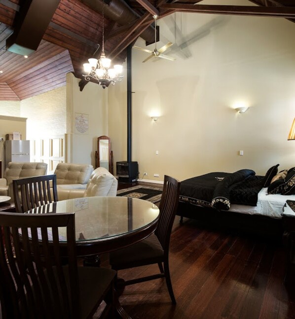 A living room with a round glass table, dark wooden chairs, a sofa, and a television.