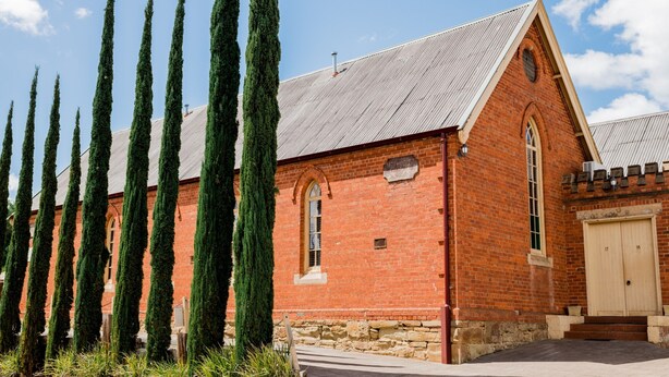 A red brick building with a gabled roof and a wooden door.