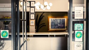 A reception area with a framed painting, framed certificates, and a reception sign.