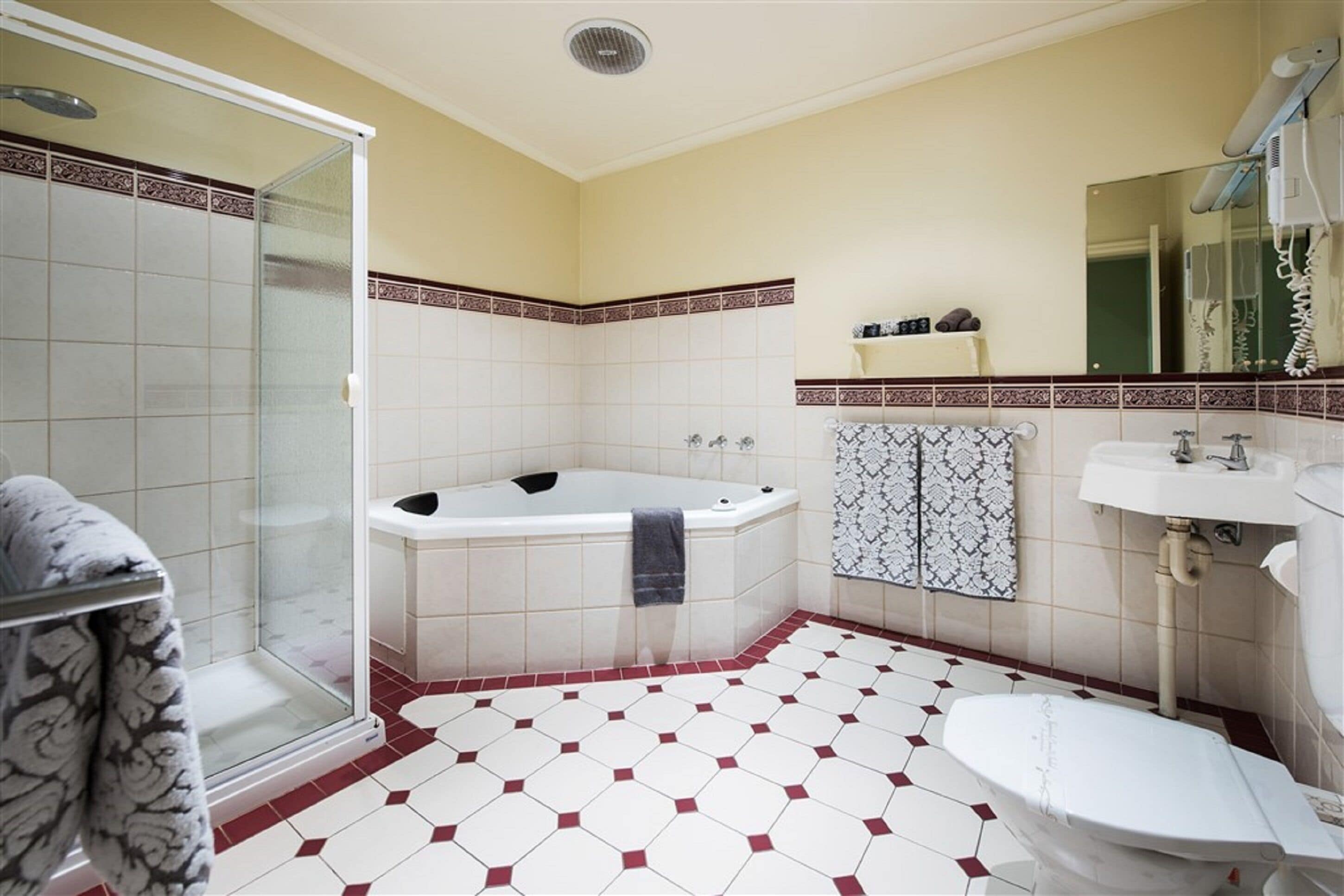 A bathroom with a glass shower enclosure, a bathtub, a toilet, and a sink.