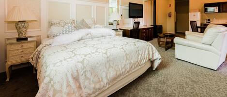 A bedroom with a large bed, a television, a desk, and a chair.