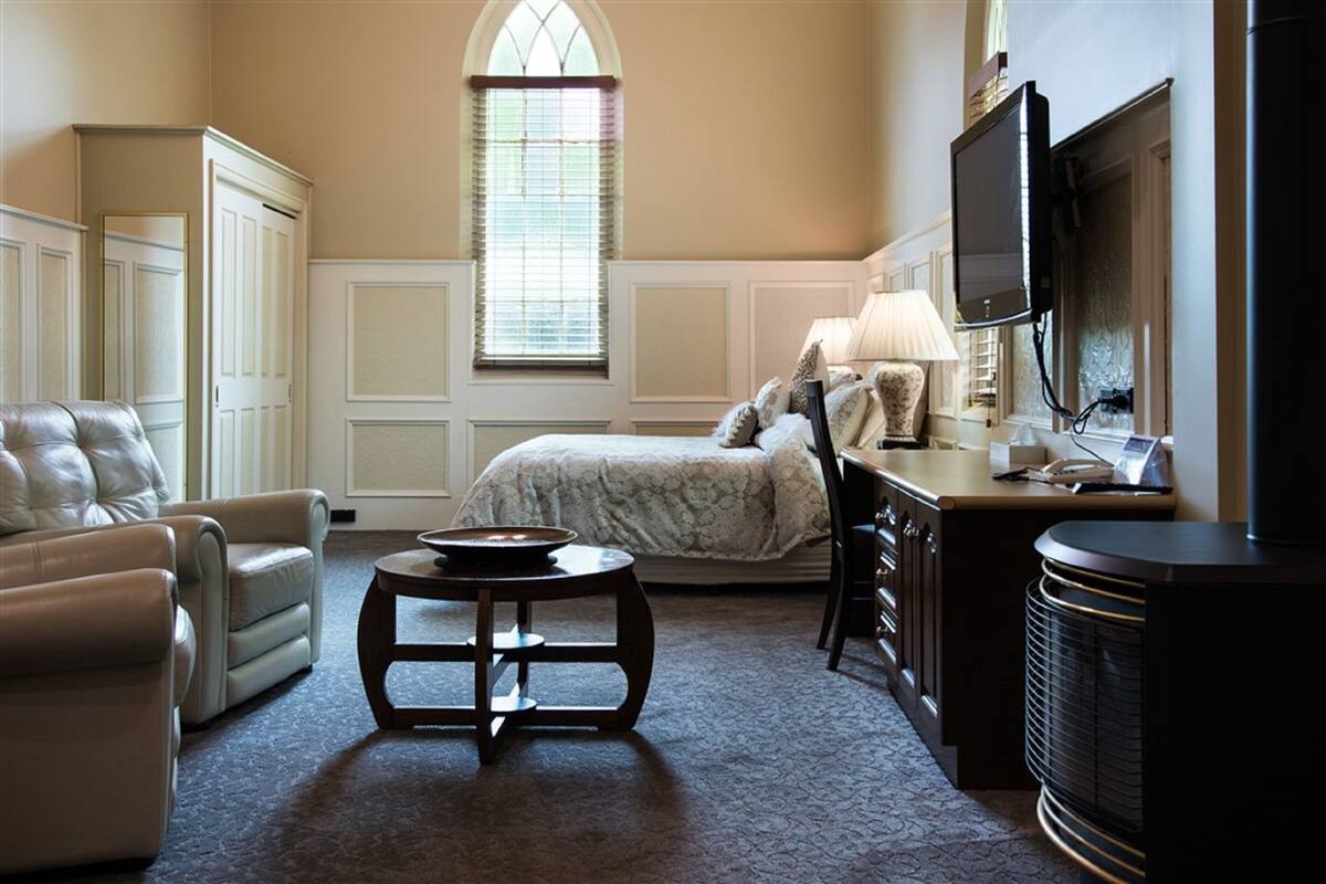A room with a bed, a desk, a chair, a television, and a heater.