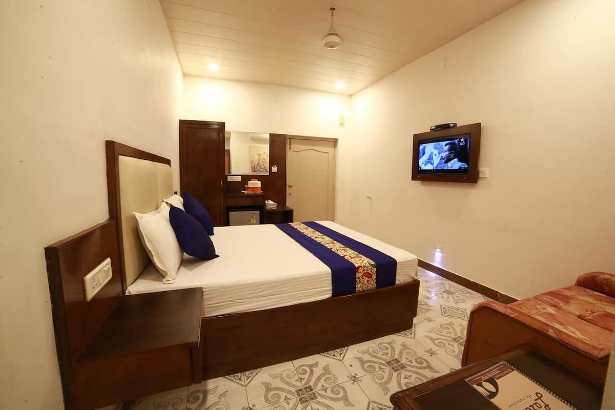 A hotel room with a bed, a television, a desk, and a chair.