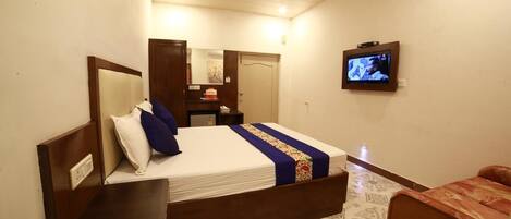Habitación de hotel con una cama, televisor, escritorio y una silla.