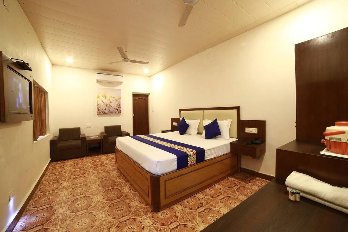 A bedroom with a large bed, a desk, a chair, a wardrobe, and a ceiling fan.
