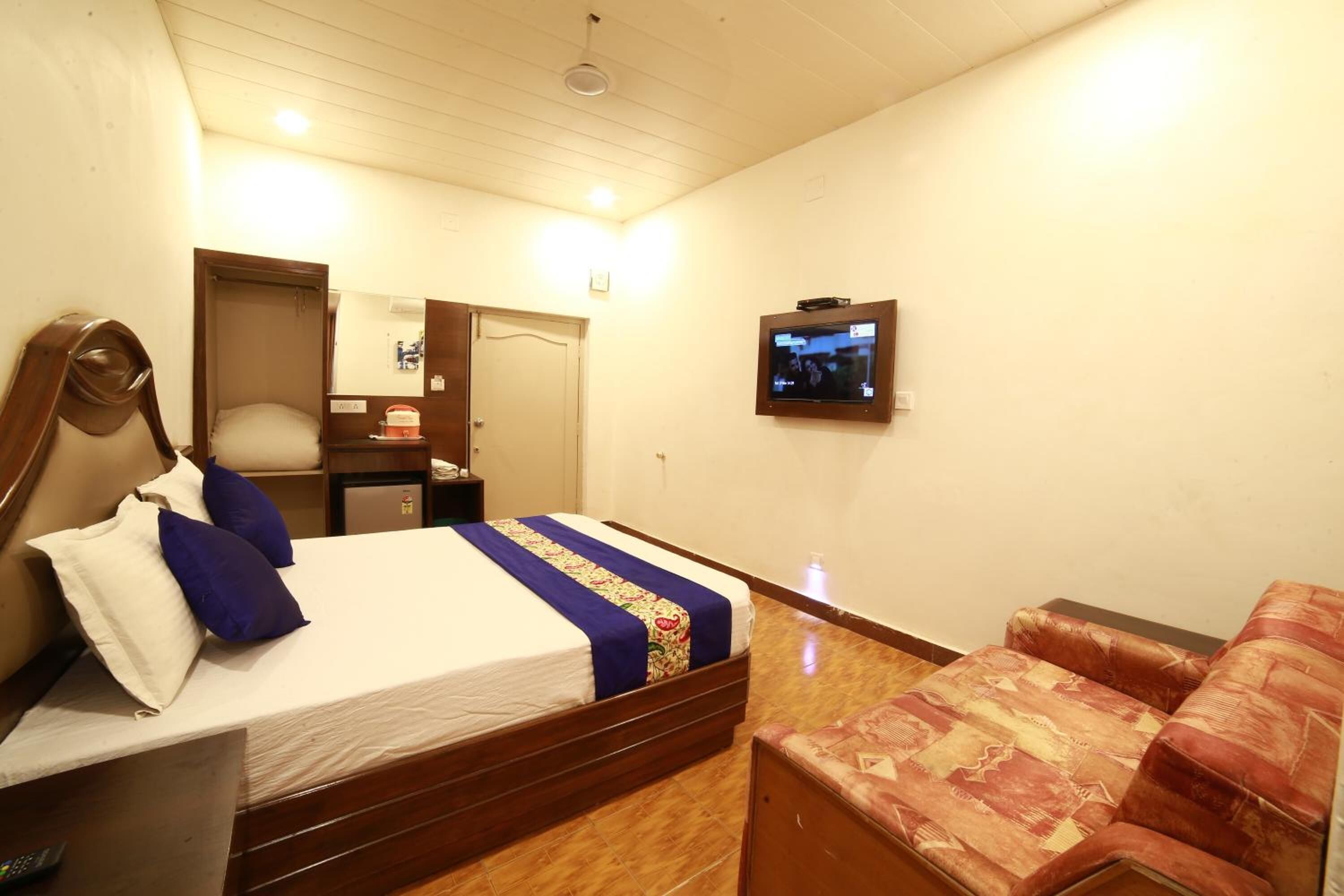 A hotel room with a bed, a television, a chair, and a small table.