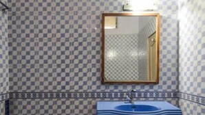 Un baño con paredes de baldosas a cuadros, un lavabo pedestal y un espejo.