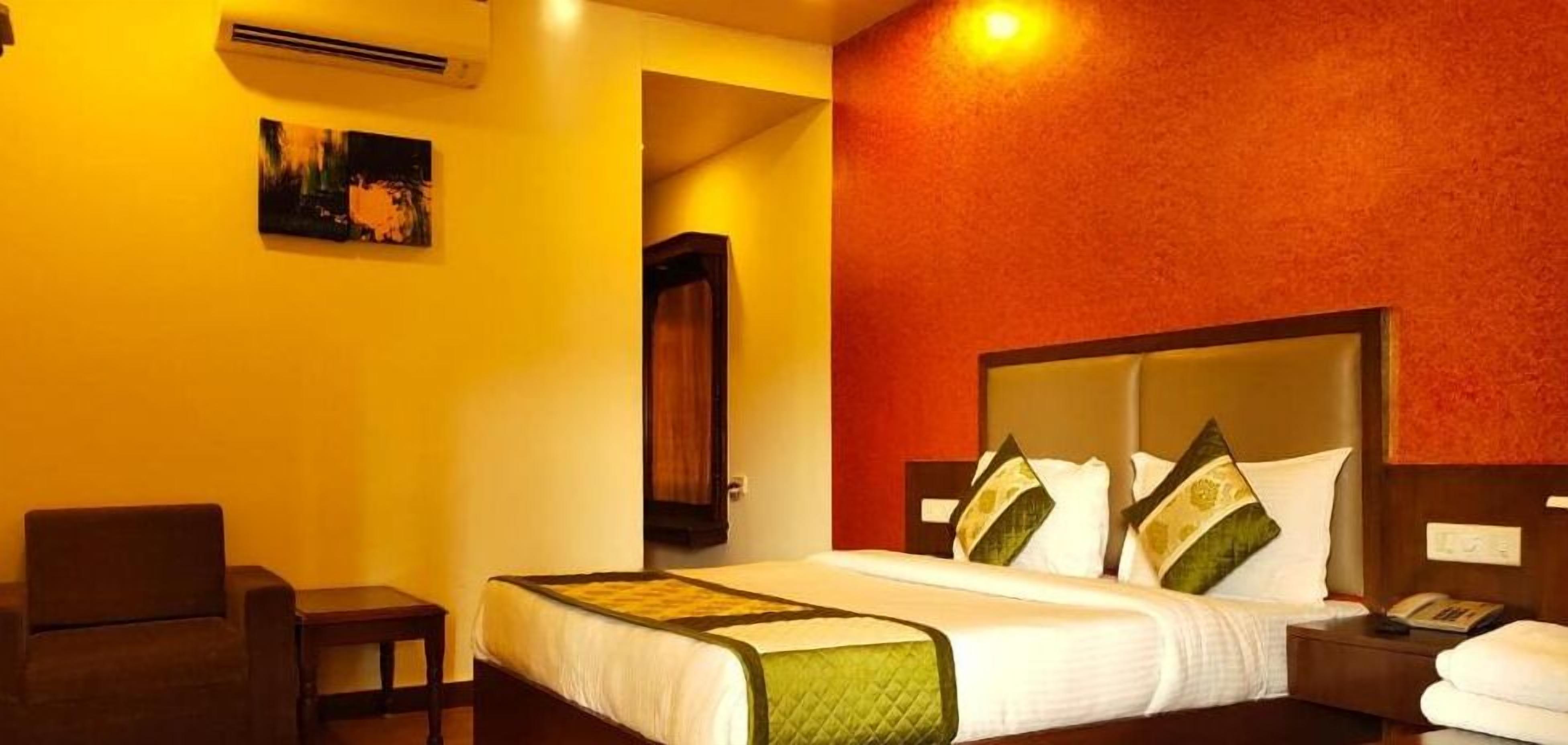 Una camera d'albergo con un letto grande, un comodino con il telefono e una sedia.