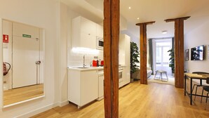 A modern kitchen with white cabinets, a wooden floor, and a visible fire extinguisher.