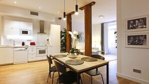 A modern kitchen with white cabinetry, a wooden dining table with black chairs, and a central island with a plant.