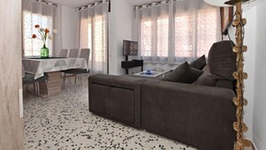 A modern living room with a sofa, a dining table, and a TV. - Magnolia by Interhome (Torredembarra)