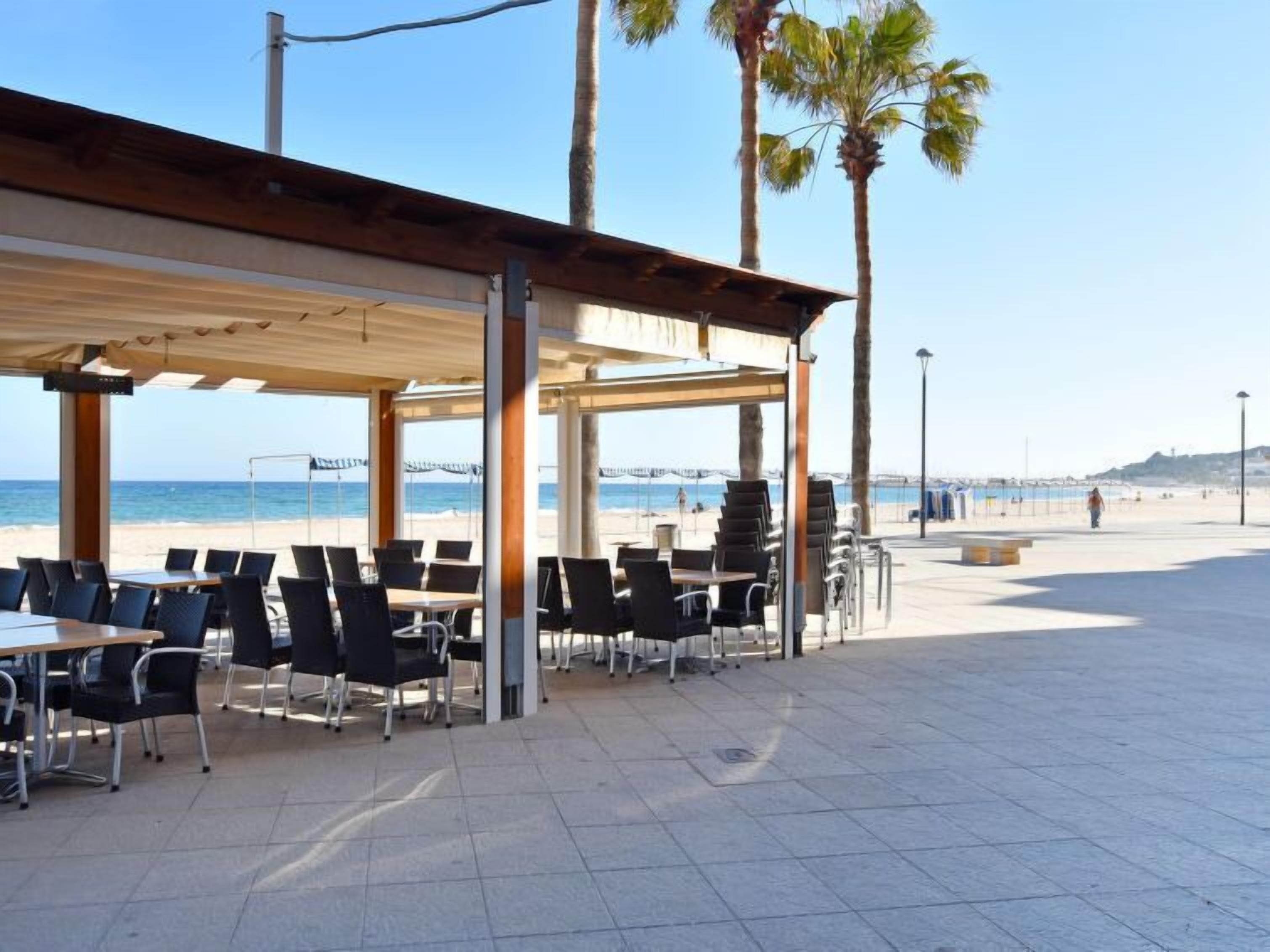 Un espace extérieur aménagé avec des tables et des chaises, donnant sur une plage.