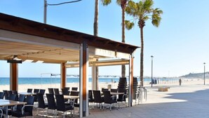 An outdoor seating area with tables and chairs, overlooking a beach. - Magnolia by Interhome (Torredembarra)