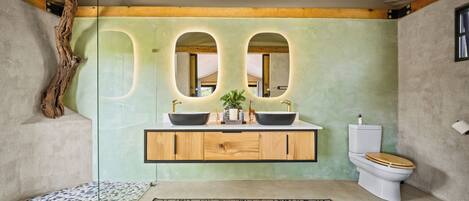 A bathroom with a wooden vanity, two sinks, a toilet, and a large mirror.