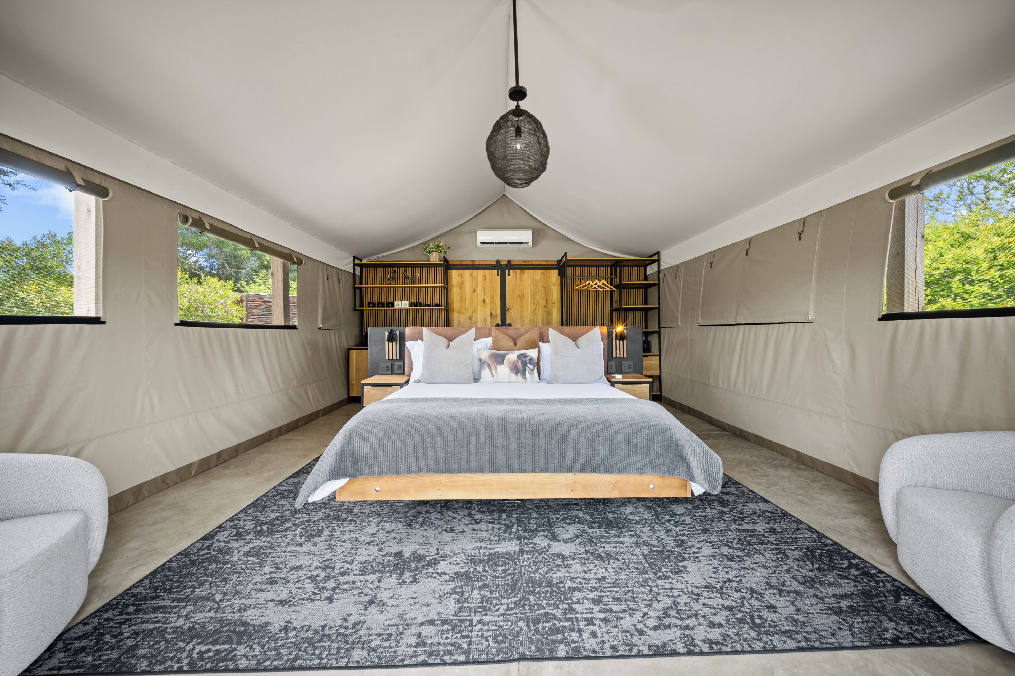 Un dormitorio con una cama grande, una lámpara colgante y vistas al exterior.