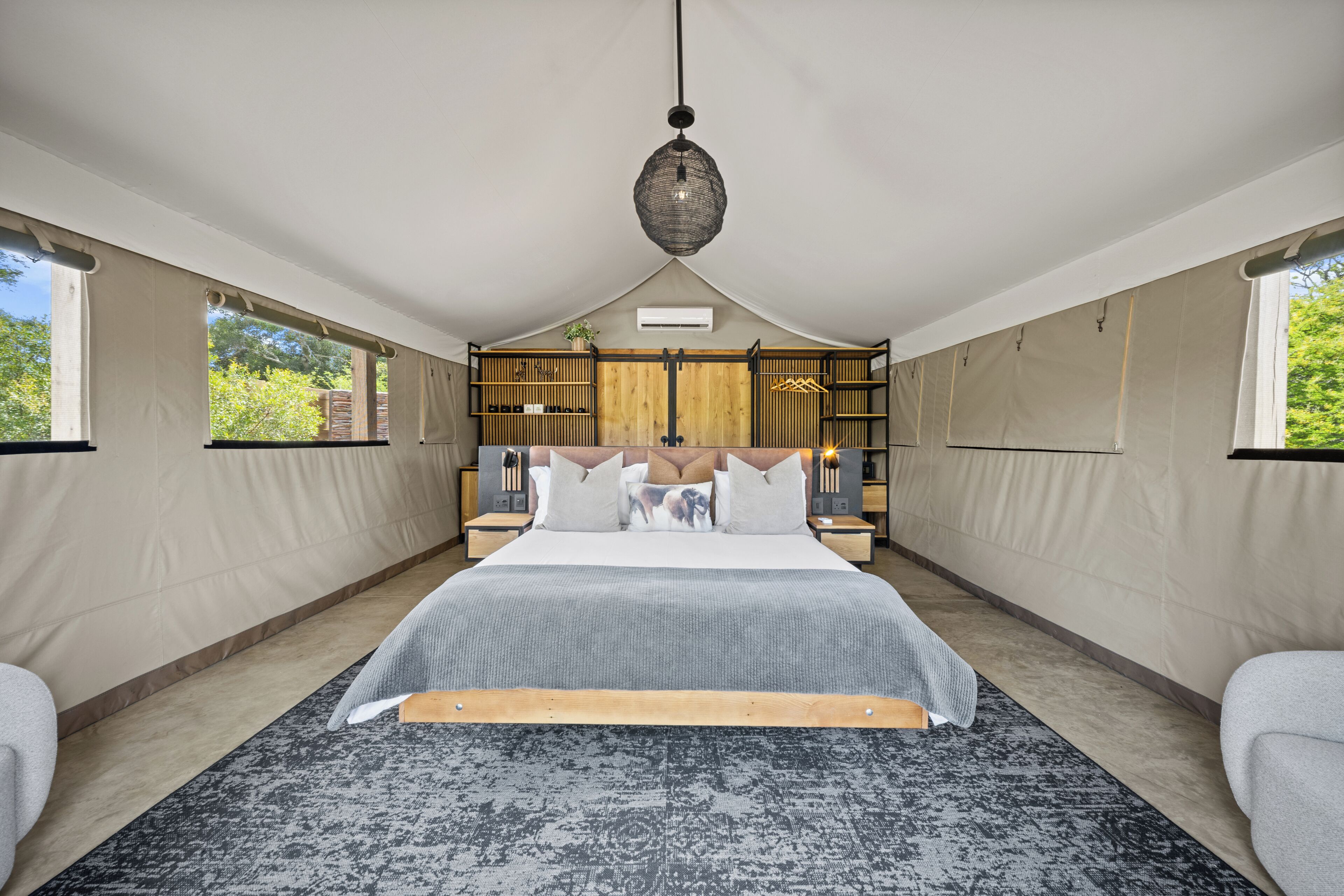 A bedroom with a large bed, a hanging light fixture, and a built-in wardrobe.